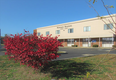 Wingard Building exterior in autumn with a bright red burning bush by the parking lot