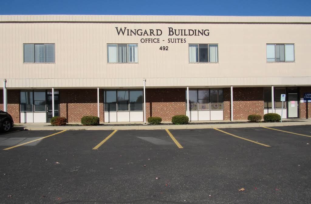 Front of the Wingard Building — a two-story tan and brick office building with covered walkway, signage reading Wingard Building Office Suites 492