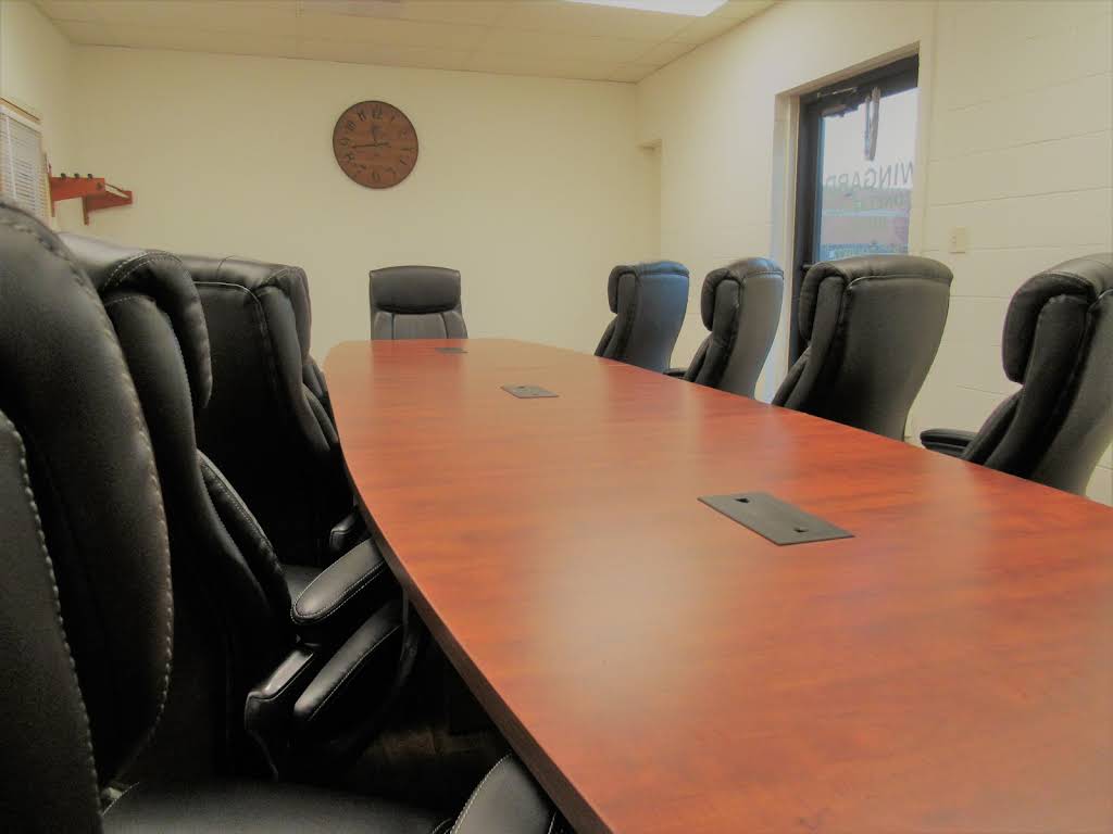 Furnished conference room with a long wood table and executive chairs