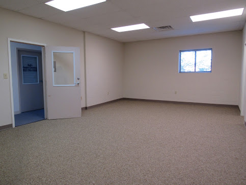 Bright empty office suite with fresh carpet, white walls, and a private entry door