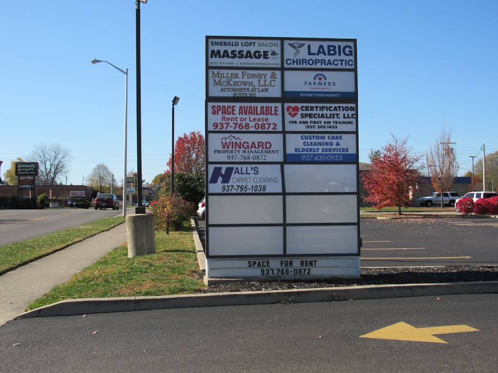The building's roadside pylon sign listing tenants including attorneys, chiropractic, insurance, and salon businesses, with a Space Available panel